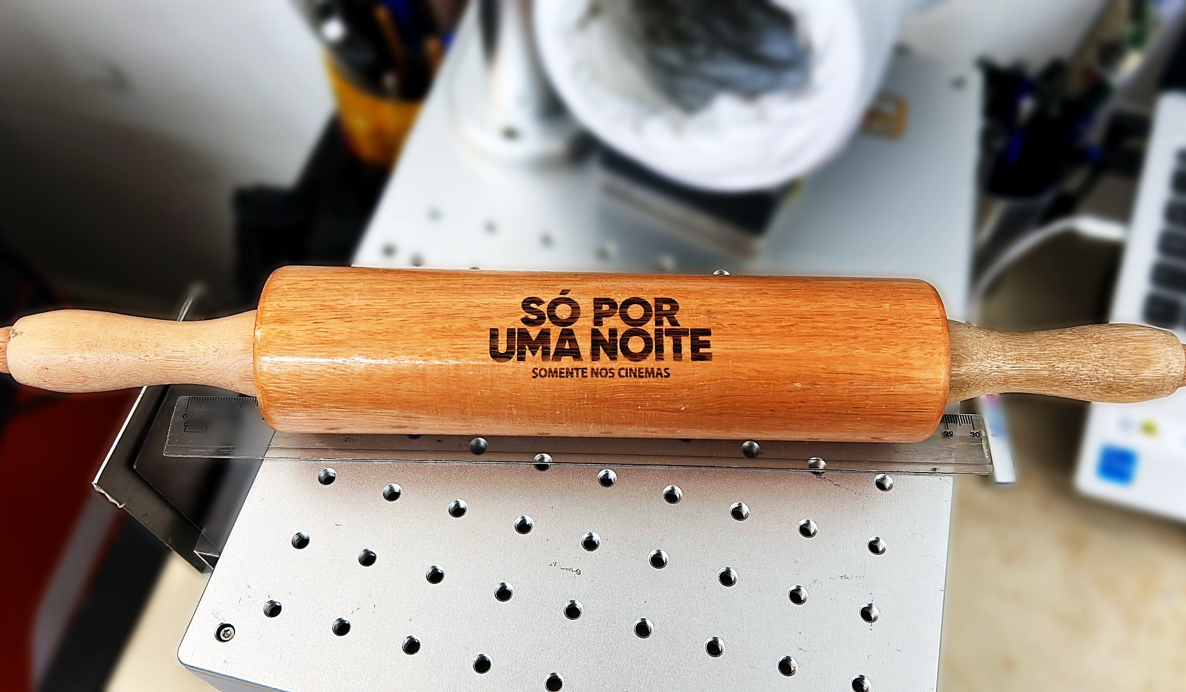 Rolo de macarrão de madeira gravado a laser, sobre a mesa perfurada da máquina